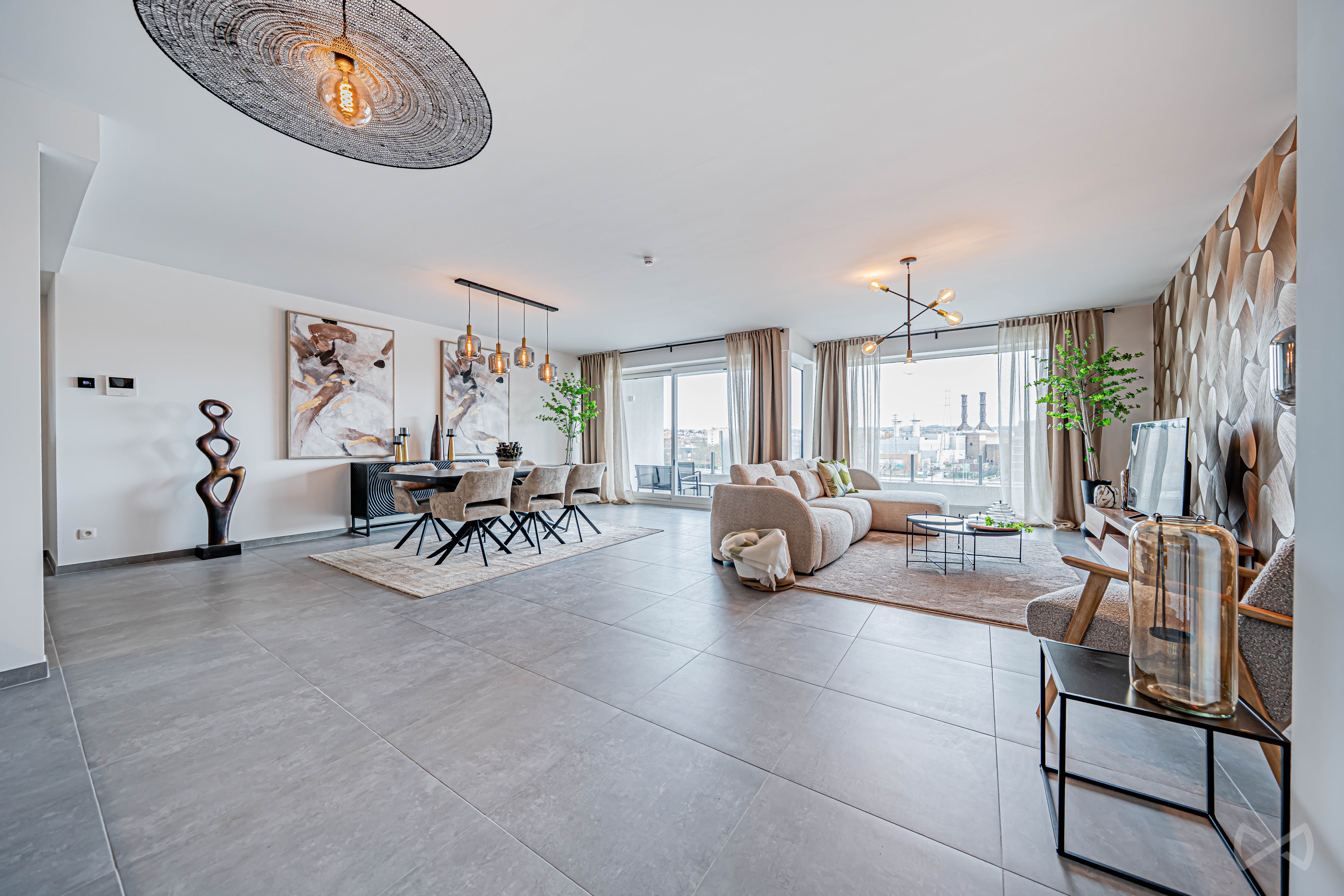 Grand séjour contemporain ouvert, combinant salon et salle à manger avec mobilier aux tons neutres et matériaux chaleureux. De larges baies vitrées apportent une forte luminosité et offrent une vue dégagée sur l’extérieur.