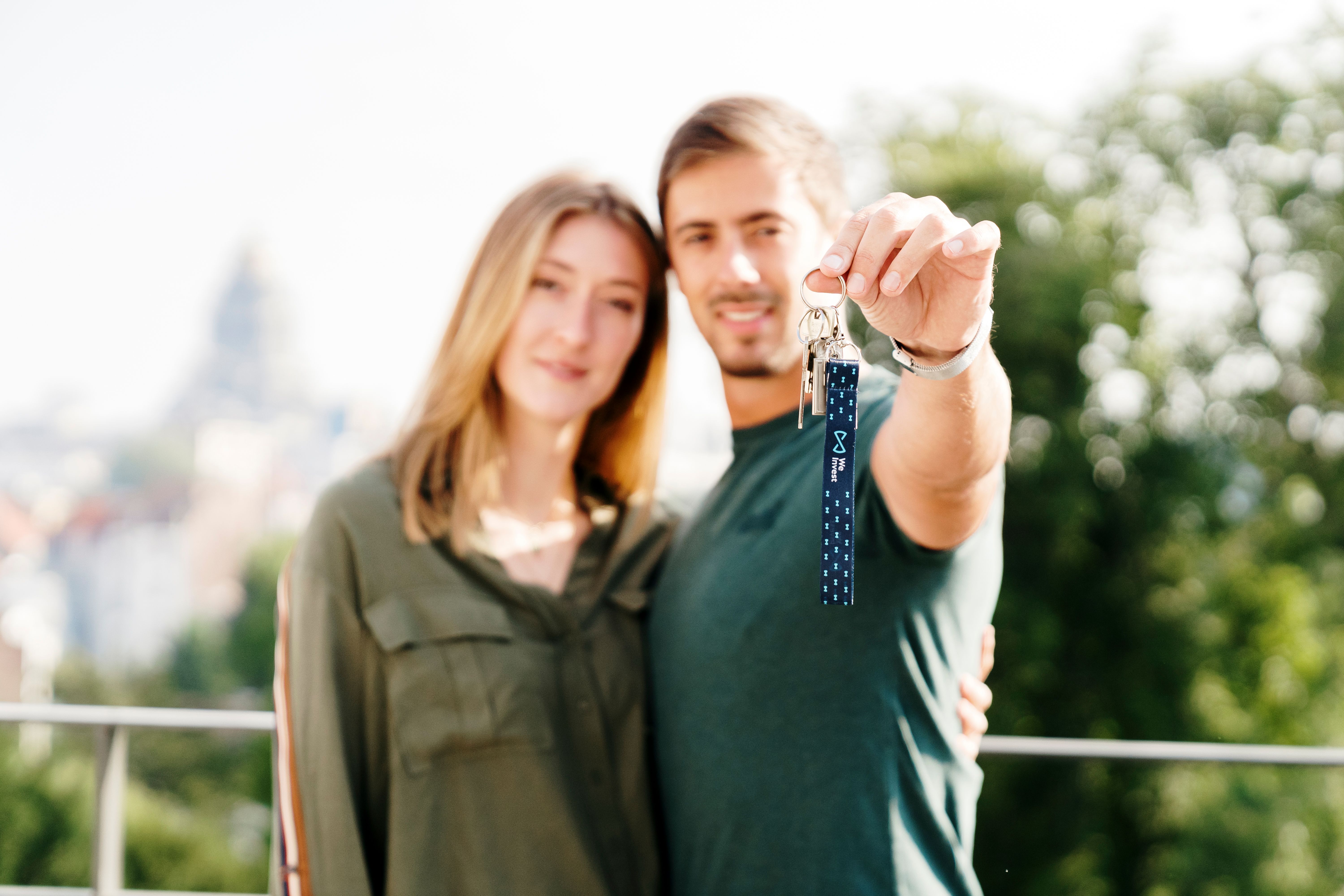 Tenants couple smiling, the man holds their new apartment keys in his hand.