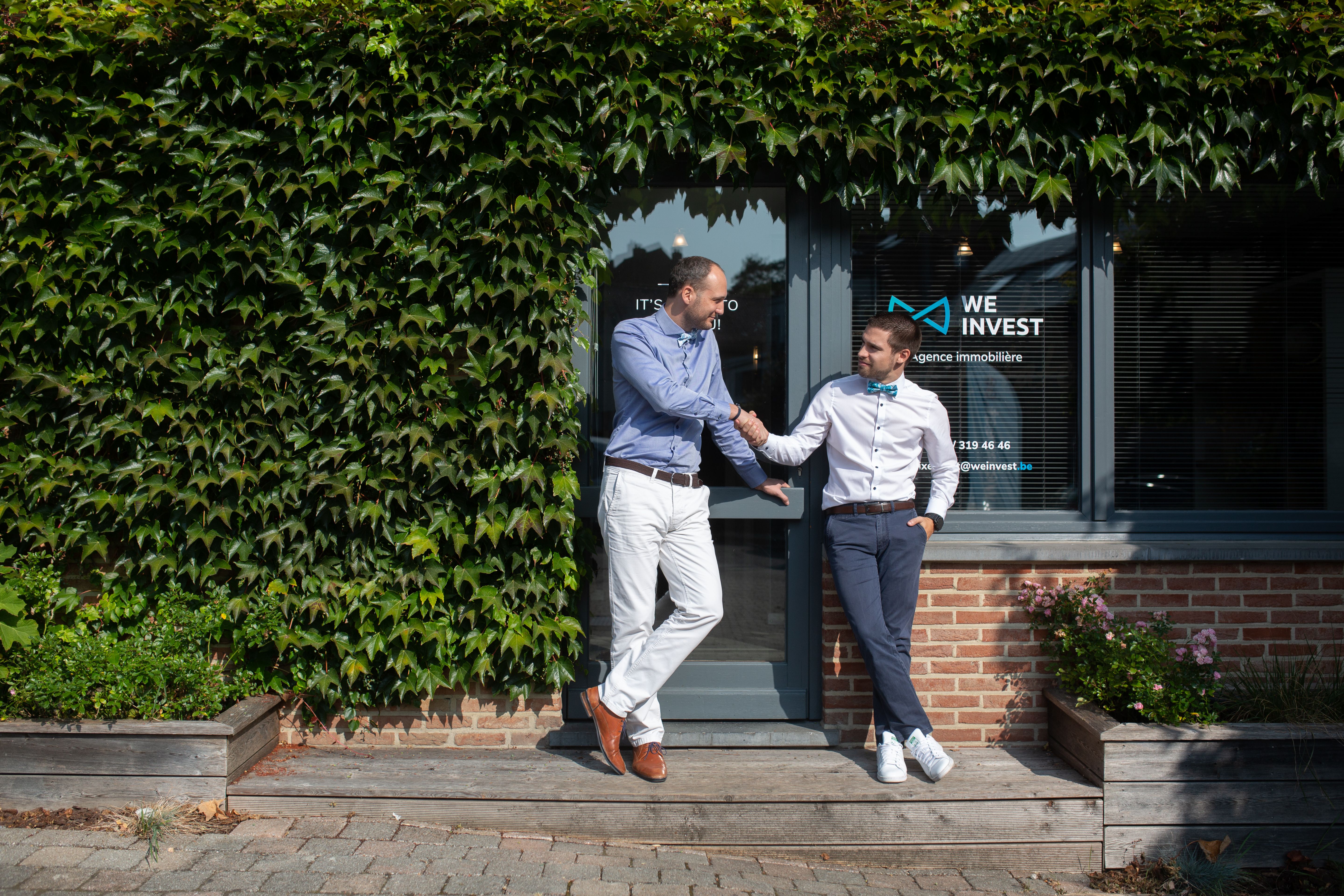 We Invest agency directors shake hands in front of their office after the opening of their real estate agency.