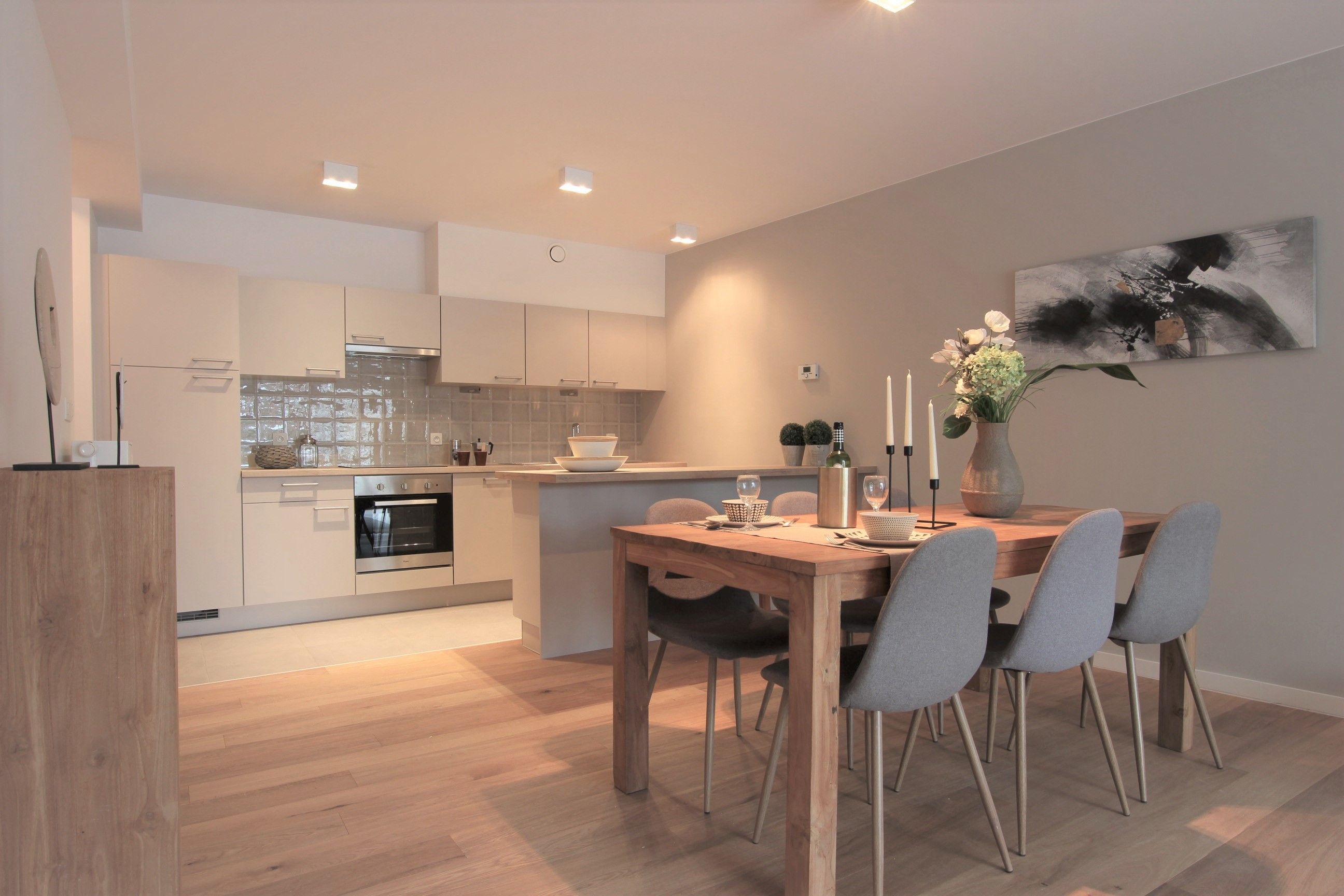 Cuisine ouverte avec coin repas, aménagée dans un style moderne et chaleureux. Les matériaux bois et les tons neutres créent une ambiance conviviale et épurée.