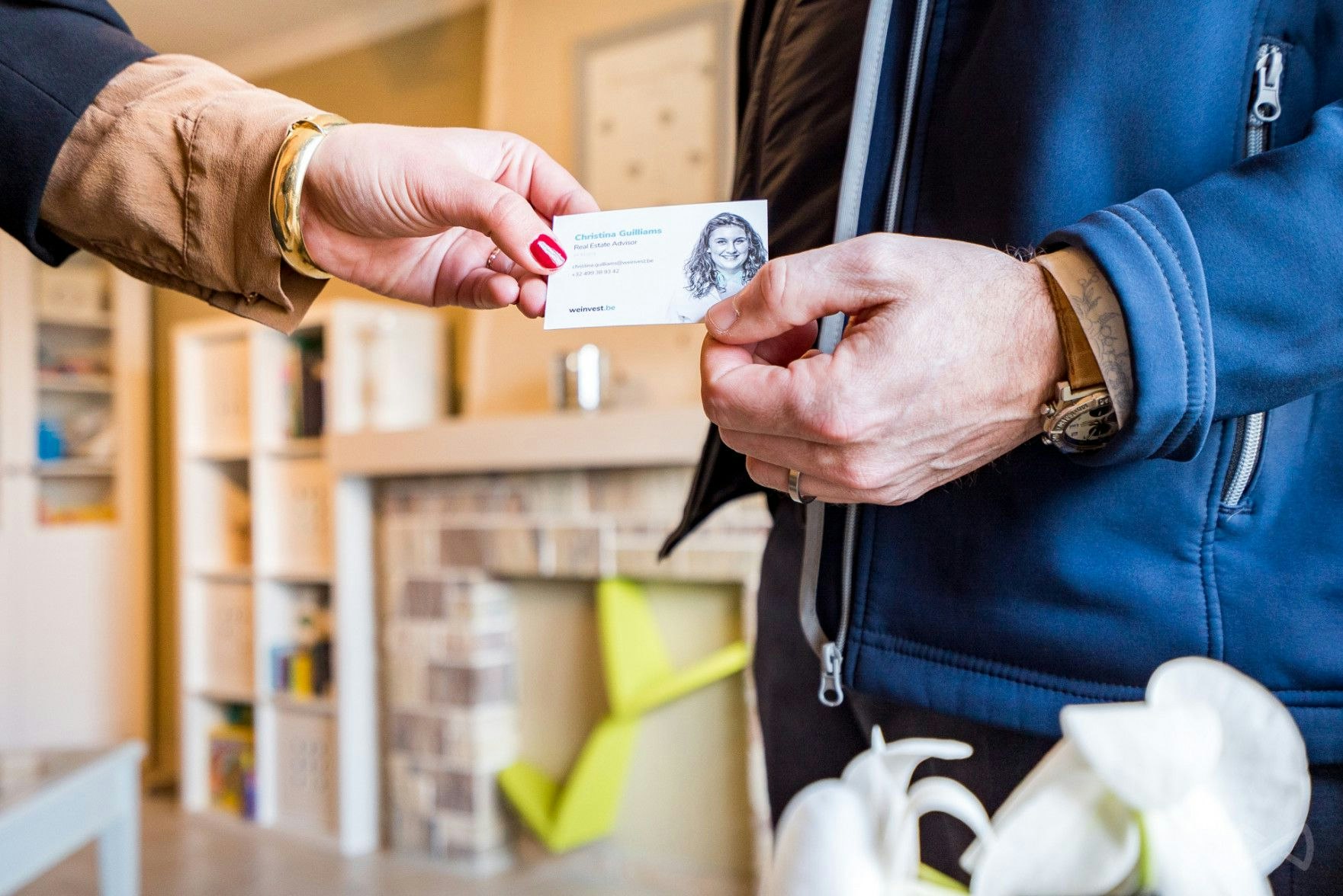 We Invest makelaar geeft zijn visitekaartje aan een potentiële verkoper tijdens een bezoek.